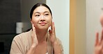 Mirror, check and woman in bathroom for skincare, grooming and dermatology for healthy skin and glow. Reflection, home and Asian person with smile, hygiene and self care with cosmetics for beauty