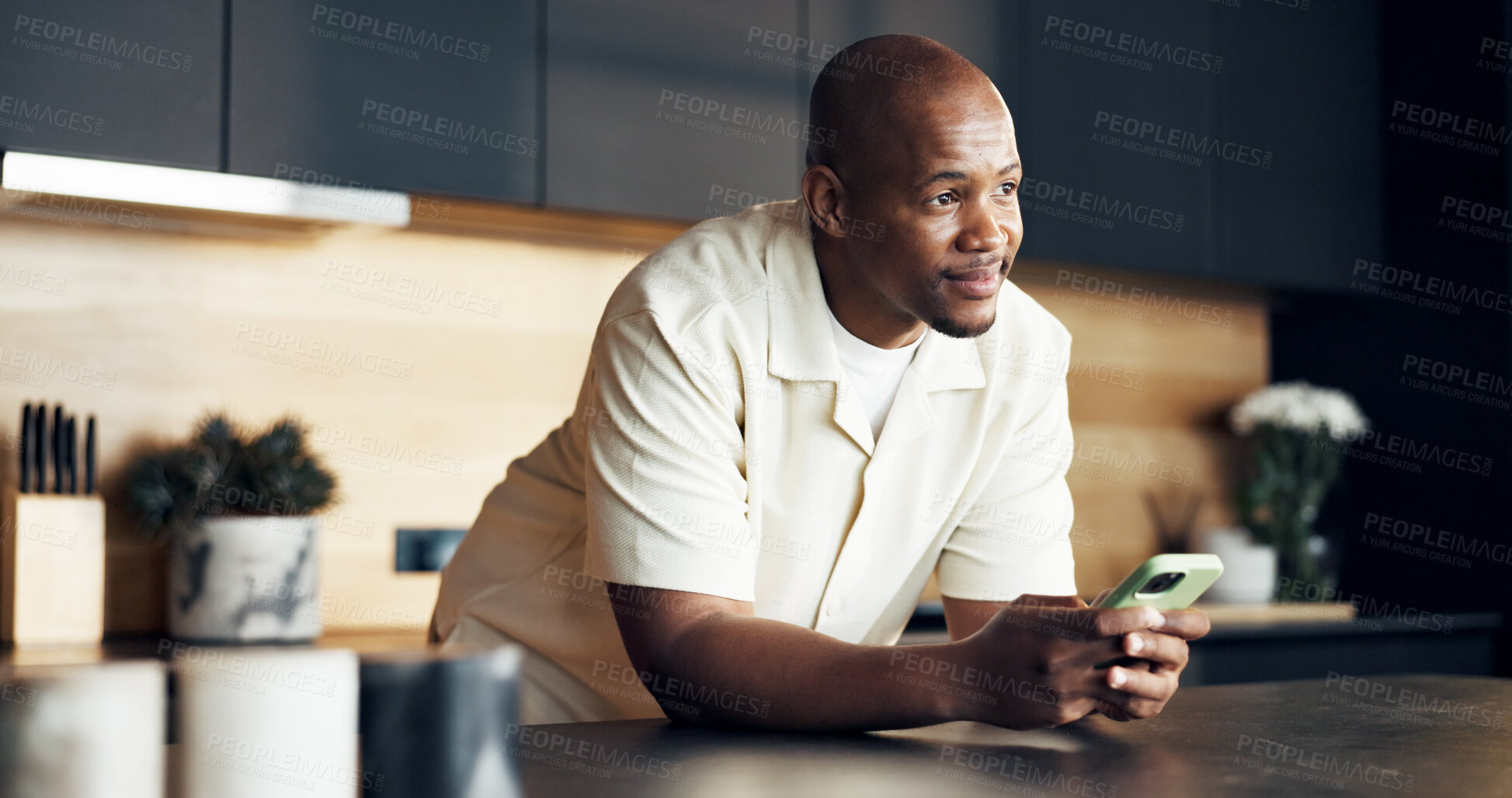 Buy stock photo Smile, man and thinking with phone in kitchen for post caption ideas, chat reflection or dating app. Happy, black person and thoughtful with mobile in home for message insight, relax or social media