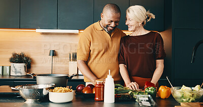 Buy stock photo Cooking, smile or couple in kitchen with help, bonding activity or connection in meal prep. Love, care or mature people in house with food, happy moment or culinary hobby in interracial relationship.