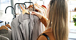 Back, clothes and woman in store, decision and shopping with fabric, options and fashion. Customer, luxury design and person in boutique, discount deal and sale for product, consumer and choose 