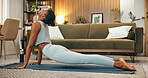 Fitness, stretching and woman with yoga in home for spinal flexibility, posture and holistic routine. Yogi, calm black person and cobra pose in living room for muscle toning, mindfulness and practice