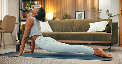 Buy stock photo Fitness, stretching and woman with yoga in home for spinal flexibility, posture and holistic routine. Yogi, calm black person and cobra pose in living room for muscle toning, mindfulness and practice