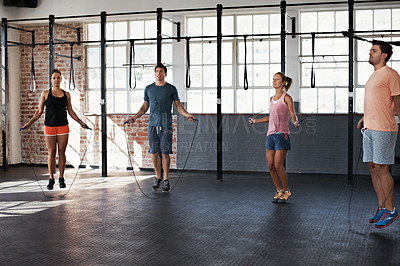 Buy stock photo Shot of a group of people jumping rope in a fitness class