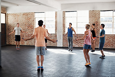 Buy stock photo Shot of a group of people jumping rope in a fitness class