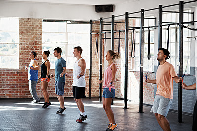 Buy stock photo Shot of a group of people jumping rope in a line in a fitness class