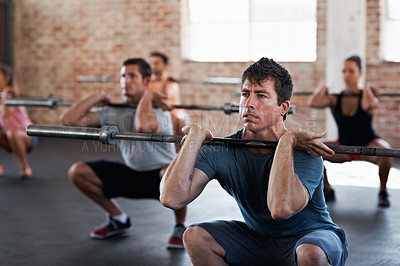Buy stock photo Shot of a group of people doing squats in a fitness workout with bars