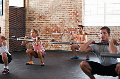 Buy stock photo Shot of a group of people doing squats in a fitness workout with bars