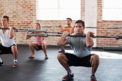Buy stock photo Shot of a group of people doing squats in a fitness workout with bars