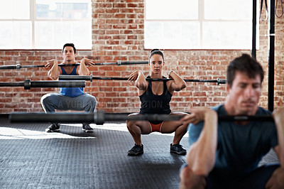Buy stock photo Shot of a group of people doing squats in a fitness workout with bars