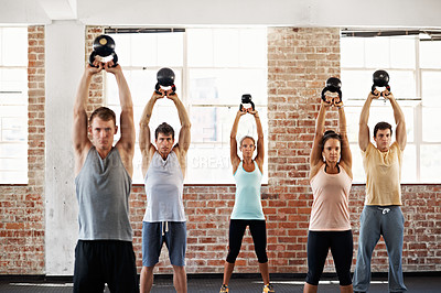 Buy stock photo Shot of a group of people lifting kettlebells in a fitness class