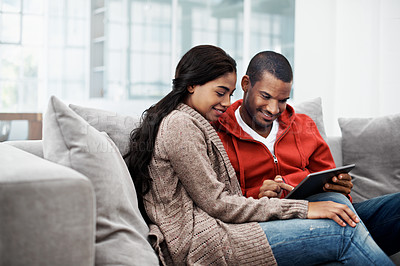 Buy stock photo Shot of a happy young couple using a digital tablet together on the sofa at home