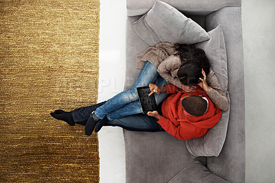 Buy stock photo Shot of a happy young couple using a digital tablet together on the sofa at home
