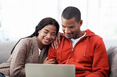 Buy stock photo Shot of a happy young couple using a laptop together on the sofa at home