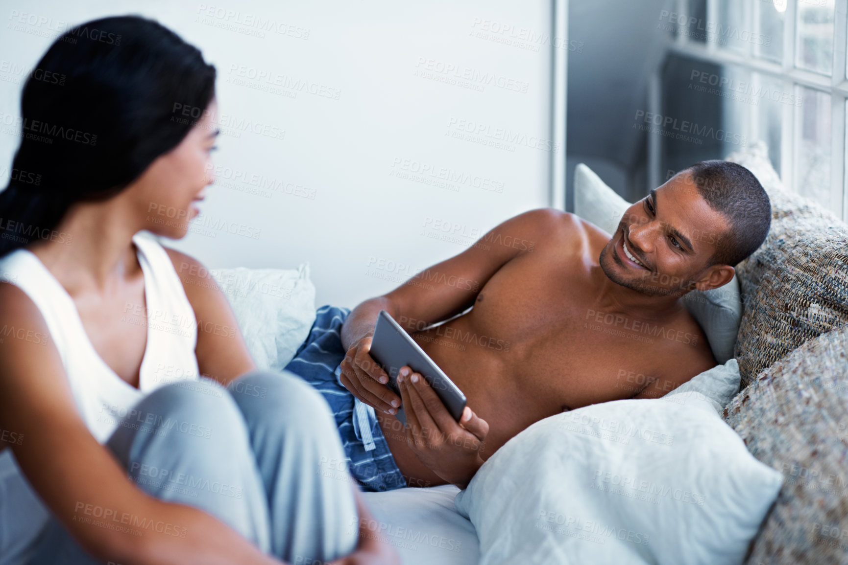 Buy stock photo Tablet, smile and couple in bed at house for bonding, social media or connection in marriage. Happy, digital technology and man with woman in bedroom for reading blog on relationship advice in home.