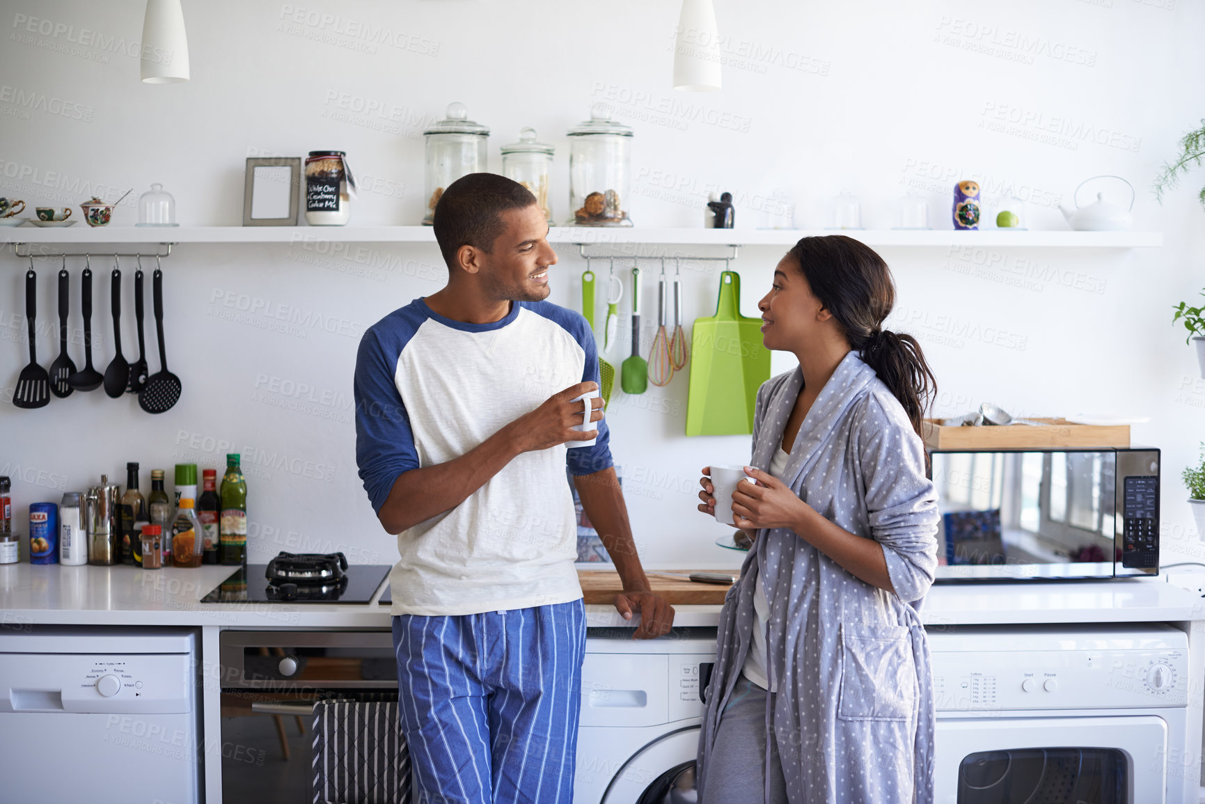 Buy stock photo African couple, coffee and love with smile in kitchen for bonding, conversation or holiday together. Gossip, happy man and woman with drink for discussion, support and morning with beverage in house