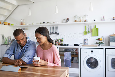 Buy stock photo Cropped shot of a young couple drinking coffee and using their tablet in the kitchen
