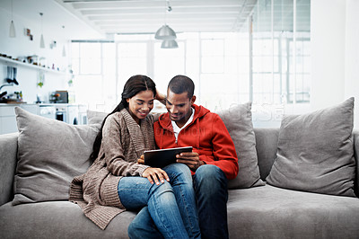 Buy stock photo Cropped shot of a young couple using their tablet while sitting on the sofa at home