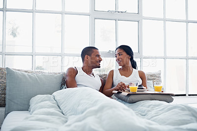 Buy stock photo Shot of a smiling young couple enjoying breakfast in bed together