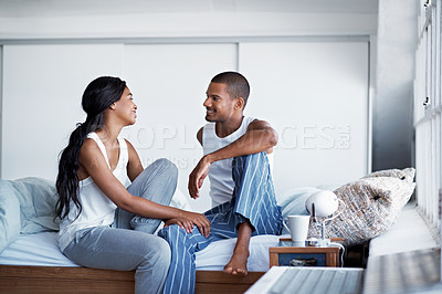 Buy stock photo Shot of a happy young couple talking together while sitting on their bed