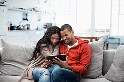 Buy stock photo Shot of a smiling young couple sitting on their sofa using a digital laptop