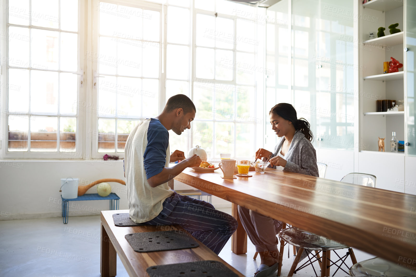 Buy stock photo Happy, couple and eating in dining room with breakfast, relax and bonding together on calm weekend. People, dating and morning in house with smile, healthy food or wellness for romantic relationship.