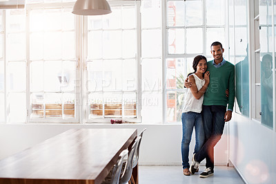 Buy stock photo Portrait of an affectionate young couple standing arm in arm in their home