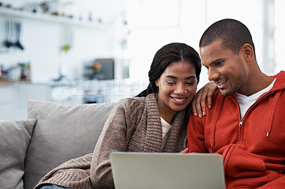 Buy stock photo Shot of a smiling young couple sitting on their sofa using a laptop