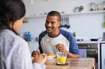 Buy stock photo Shot of a young couple eating breakfast together in their kitchen