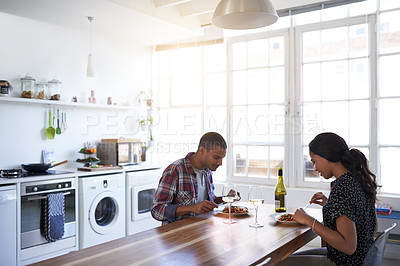 Buy stock photo Shot of a young couple talking together over dinner in their kitchen