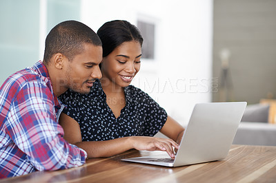 Buy stock photo Shot of a young couple sitting at their dining table using a laptop