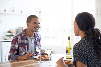 Buy stock photo Shot of a young couple eating dinner in their kitchen