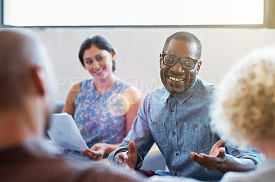 Buy stock photo Shot of a group of smiling colleagues talking together while sitting on a sofa in a modern office