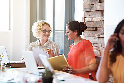 Buy stock photo Shot of two coworkers discussing paperwork at a desk in an office