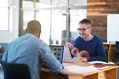 Buy stock photo Shot of two men working together at a table in an office