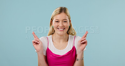 Buy stock photo Portrait, happy woman and fingers crossed for wish in studio, hope and space on blue background. Smile, person and hand gesture for expectation, good luck sign or pray with optimism for success