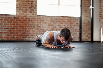 Buy stock photo Shot of a young man in a gym doing pushups