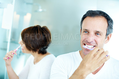 Buy stock photo Mature, man and brushing teeth in bathroom with morning routine, dental care and grooming for wellness. Couple, smile and cleaning mouth in home with toothbrush, oral hygiene or healthy relationship.