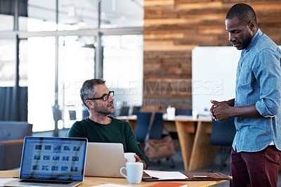 Buy stock photo Shot of  two male coworkers talking together at a desk in an office