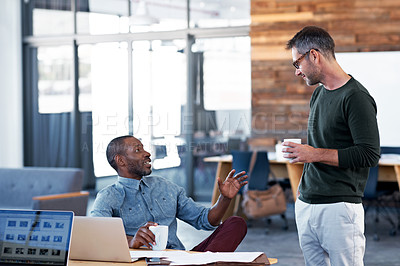 Buy stock photo Shot of  two male coworkers talking together at a desk in an office
