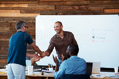 Buy stock photo Shot of two coworkers shaking hands during an office presentation
