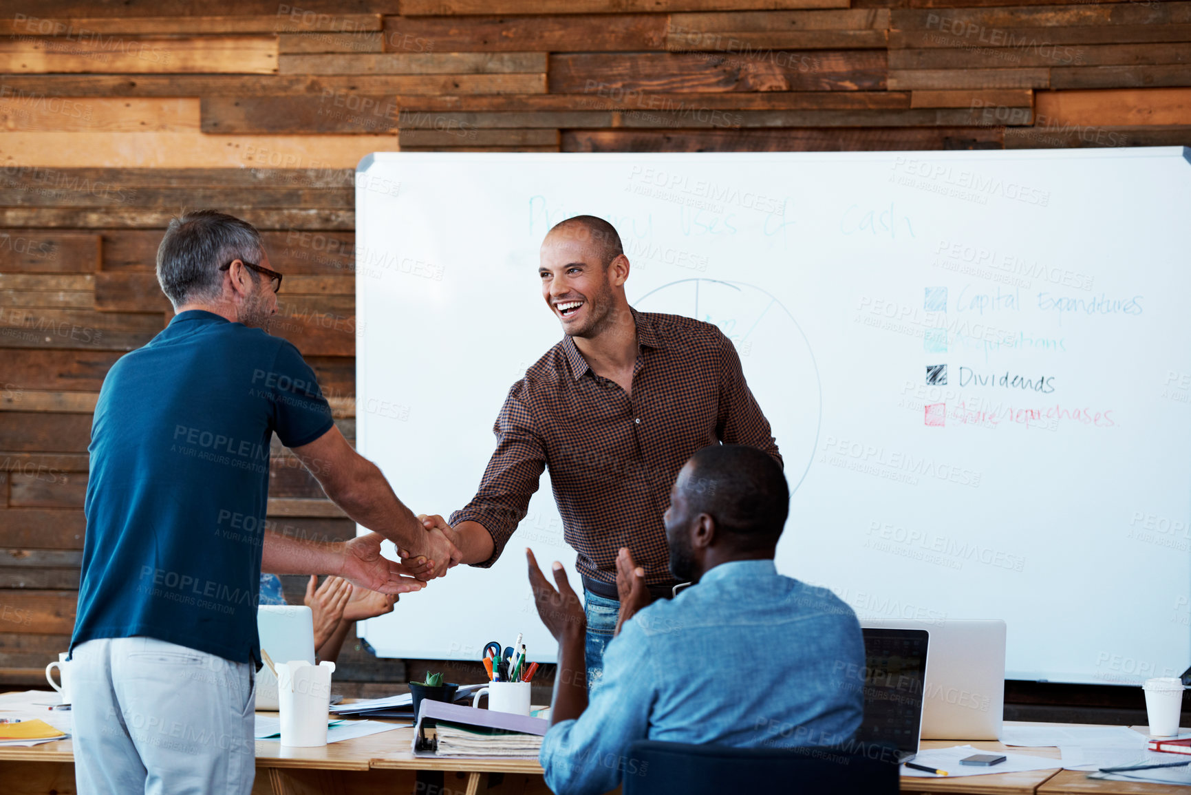 Buy stock photo Shot of two coworkers shaking hands during an office presentation