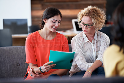 Buy stock photo Shot of two female coworkers discussing paperwork while sitting in an office
