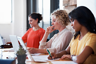 Buy stock photo Shot of a group of female colleagues at work on laptops in an office