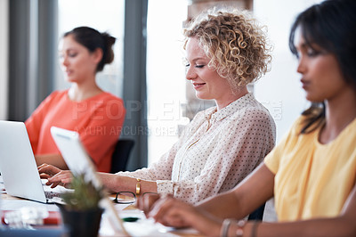 Buy stock photo Shot of a group of female colleagues at work on laptops in an office