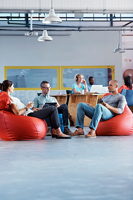 Buy stock photo Shot of a group of colleagues sitting in bean bag chairs while working in an office