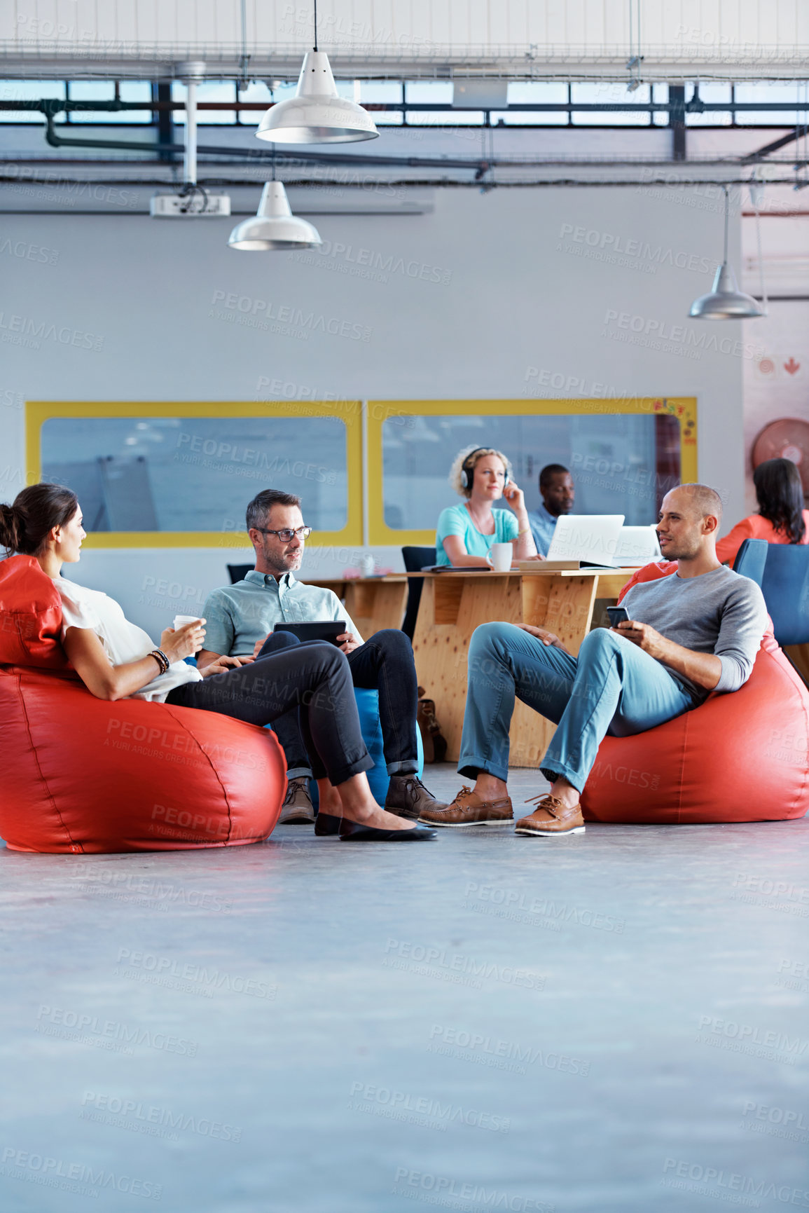 Buy stock photo Shot of a group of colleagues sitting in bean bag chairs while working in an office