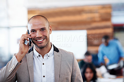 Buy stock photo Shot of an office worker talking on his cellphone with colleagues in the background