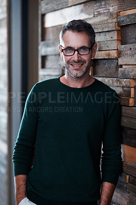 Buy stock photo Portrait of a handsome businessman leaning against a wall in an office