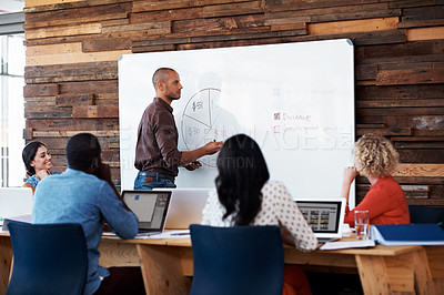 Buy stock photo Shot of a male office worker giving a financial presentation to her colleagues