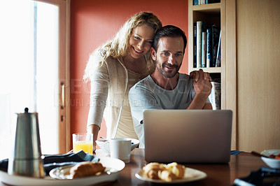 Buy stock photo Cropped shot of a couple using a laptop in the middle of breakfast